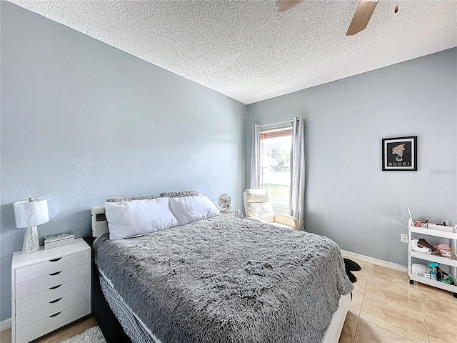 bedroom with a textured ceiling, ceiling fan, and light tile patterned floors