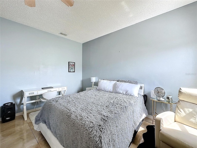 bedroom with a textured ceiling, ceiling fan, and light tile patterned floors