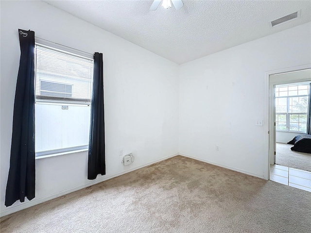 spare room featuring a textured ceiling, ceiling fan, and light colored carpet