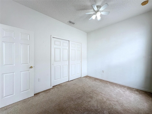 unfurnished bedroom with a textured ceiling, ceiling fan, carpet flooring, and a closet