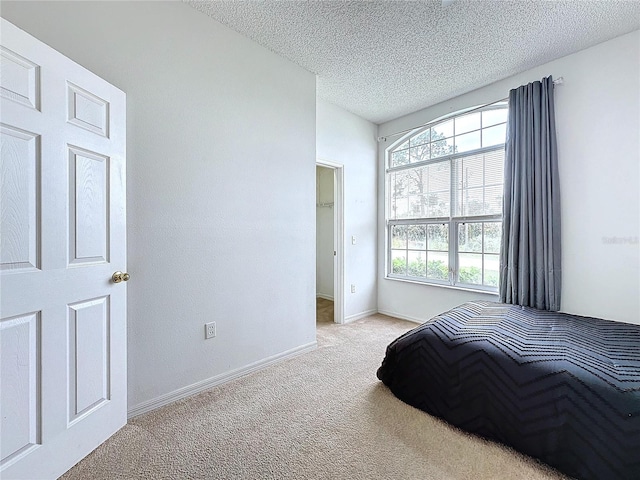 bedroom with light colored carpet and a textured ceiling