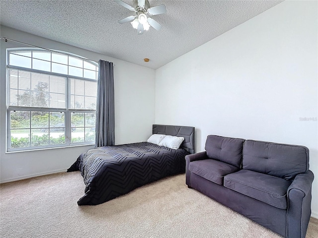 bedroom with a textured ceiling, ceiling fan, and light carpet