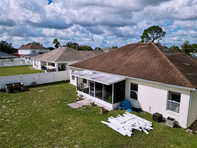 rear view of property featuring a sunroom and a lawn