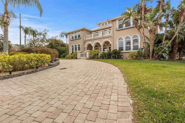 1665 Blue Heron Ln, Lakeland, FL 33813 - mediterranean / spanish-style house with a balcony, a front lawn, curved driveway, and stucco siding