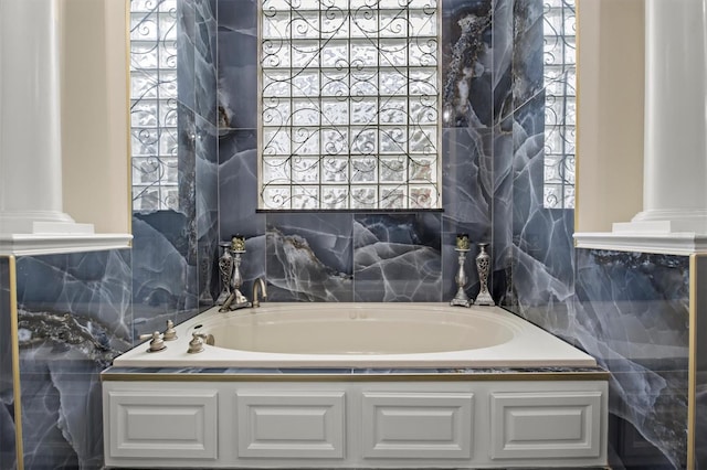 1665 Blue Heron Ln, Lakeland, FL 33813 - bathroom featuring tile walls, a garden tub, ornate columns, and healthy amount of natural light
