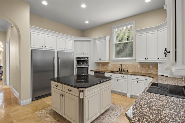 1665 Blue Heron Ln, Lakeland, FL 33813 - kitchen featuring stainless steel appliances, a sink, arched walkways, tasteful backsplash, and recessed lighting
