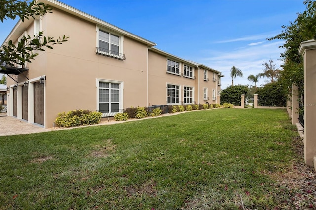 1665 Blue Heron Ln, Lakeland, FL 33813 - back of house with stucco siding, a lawn, driveway, and an attached garage