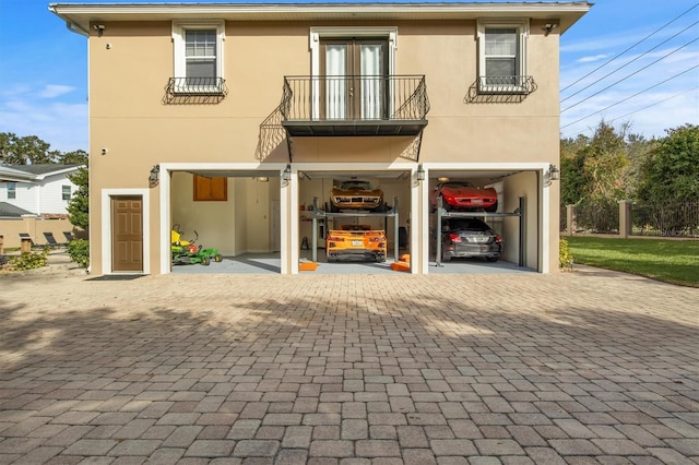 1665 Blue Heron Ln, Lakeland, FL 33813 - rear view of house featuring stucco siding, a balcony, fence, and decorative driveway