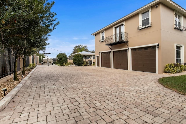 1665 Blue Heron Ln, Lakeland, FL 33813 - view of home's exterior with a balcony, stucco siding, an attached garage, decorative driveway, and fence