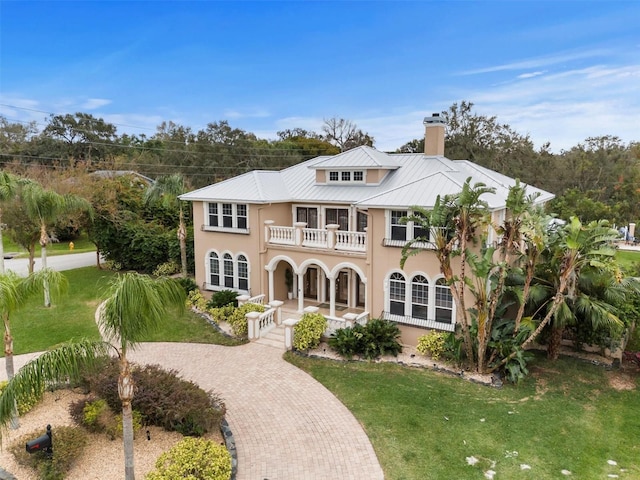 1665 Blue Heron Ln, Lakeland, FL 33813 - view of front facade featuring a balcony, covered porch, a chimney, stucco siding, and a front lawn
