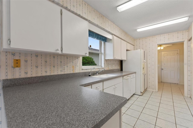 kitchen featuring sink, white appliances, white cabinetry, a textured ceiling, and light tile patterned floors