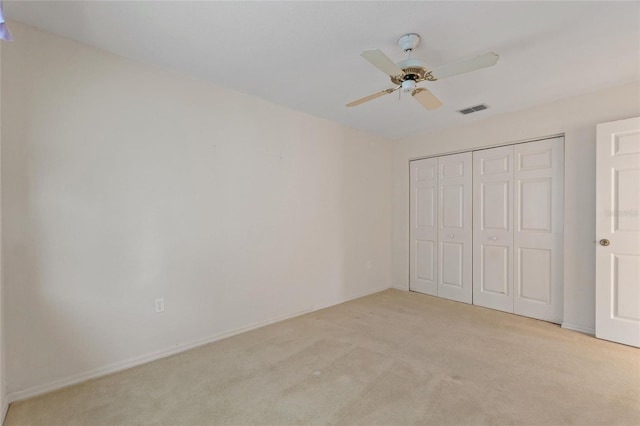 unfurnished bedroom with ceiling fan, a closet, and light carpet