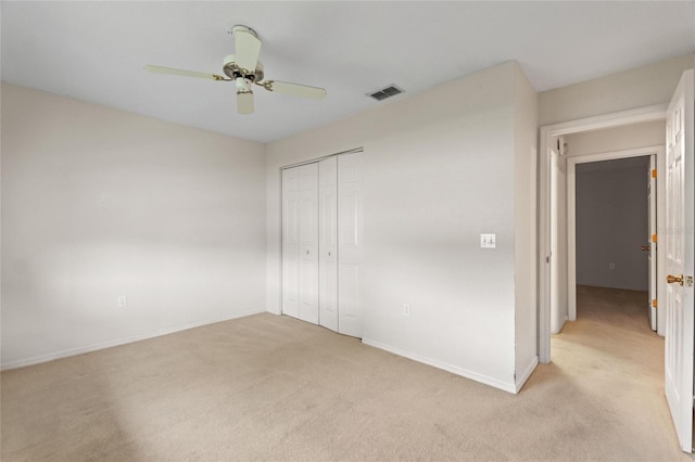 unfurnished bedroom featuring ceiling fan, light colored carpet, and a closet