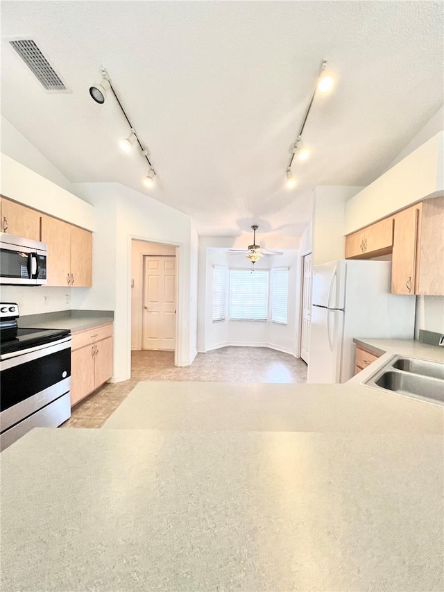 kitchen featuring stainless steel appliances, sink, light brown cabinets, and ceiling fan