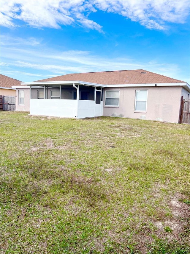 rear view of house featuring a sunroom and a yard