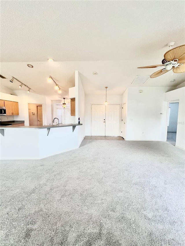 unfurnished living room featuring a textured ceiling, light colored carpet, and ceiling fan