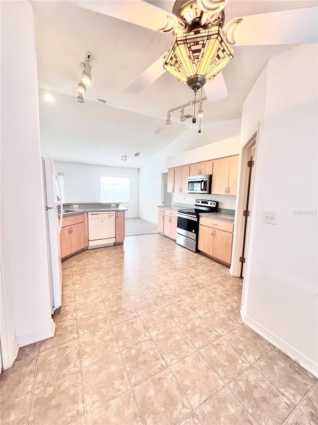 kitchen with vaulted ceiling, light brown cabinets, and appliances with stainless steel finishes