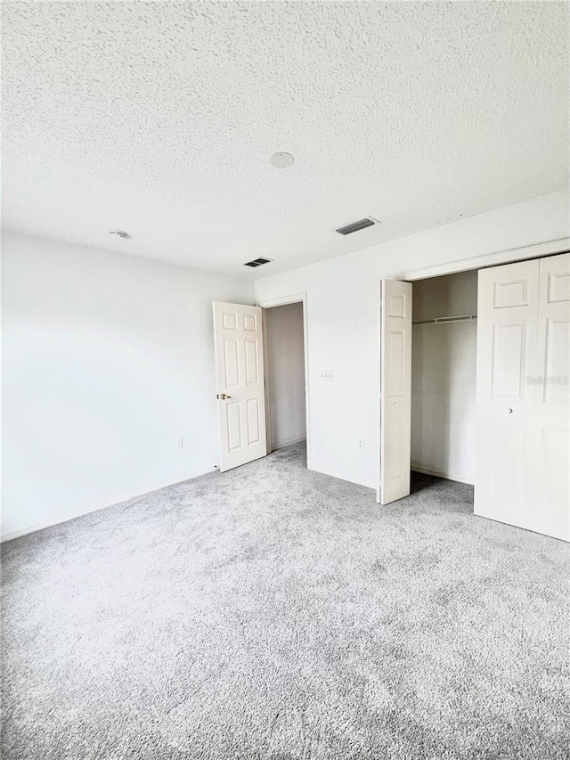 unfurnished bedroom featuring carpet floors, a textured ceiling, and a closet