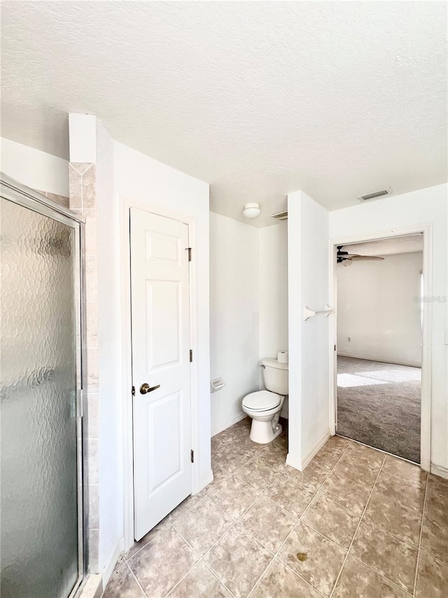 bathroom featuring walk in shower, tile patterned floors, a textured ceiling, and toilet