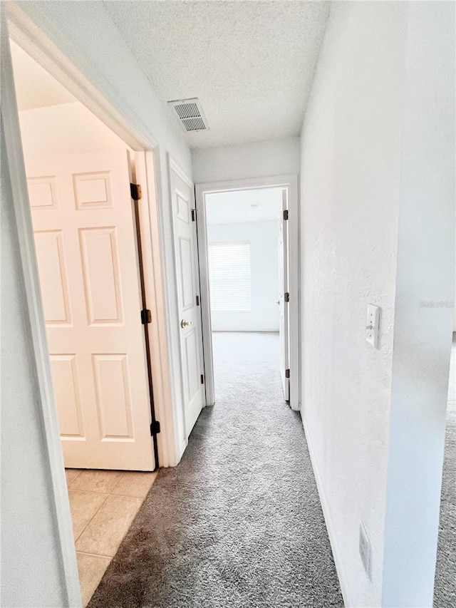 hall featuring light colored carpet and a textured ceiling