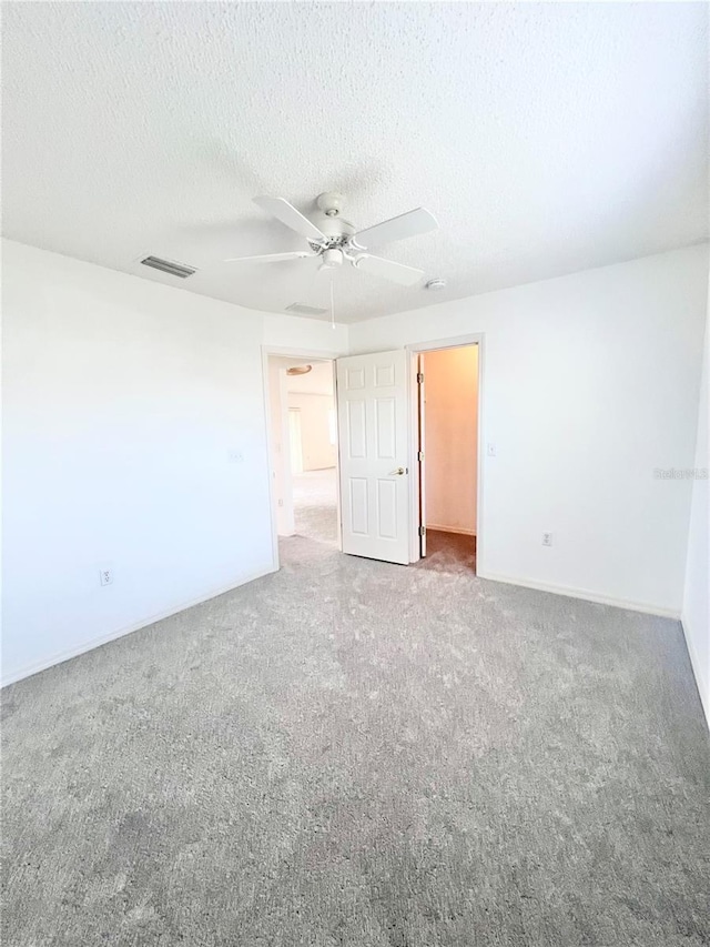 empty room with ceiling fan, carpet floors, and a textured ceiling