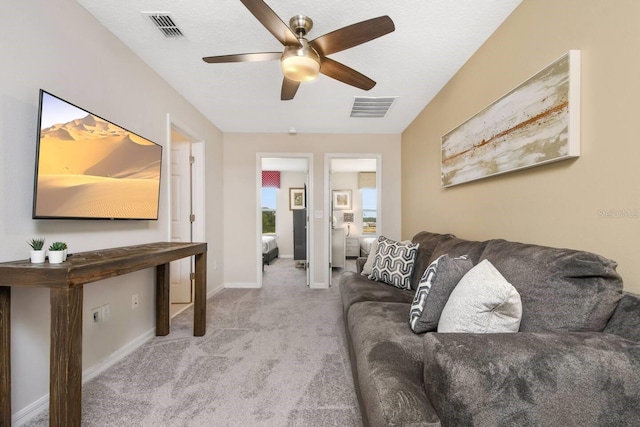 carpeted living room with ceiling fan and a textured ceiling