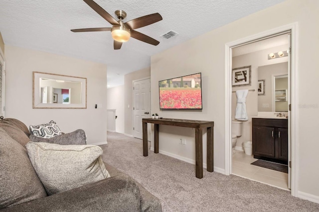 carpeted living room with ceiling fan and a textured ceiling