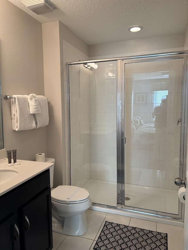 bathroom with toilet, vanity, tile patterned flooring, a shower with shower door, and a textured ceiling