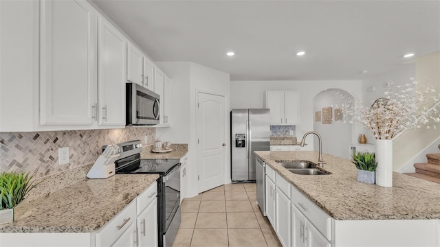 kitchen with sink, appliances with stainless steel finishes, white cabinetry, tasteful backsplash, and an island with sink