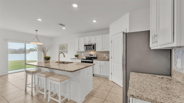 kitchen with sink, stainless steel appliances, white cabinets, and light stone countertops