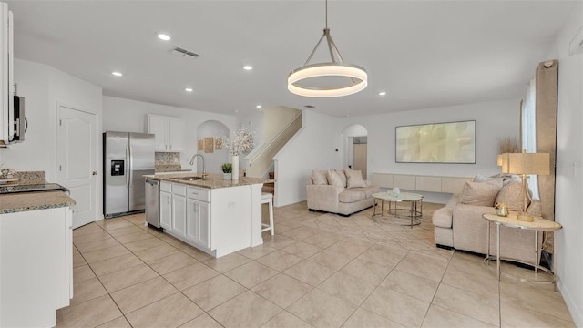 kitchen featuring white cabinetry, appliances with stainless steel finishes, decorative light fixtures, and sink