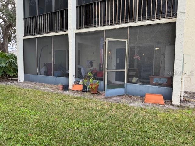 rear view of property featuring a yard and a sunroom