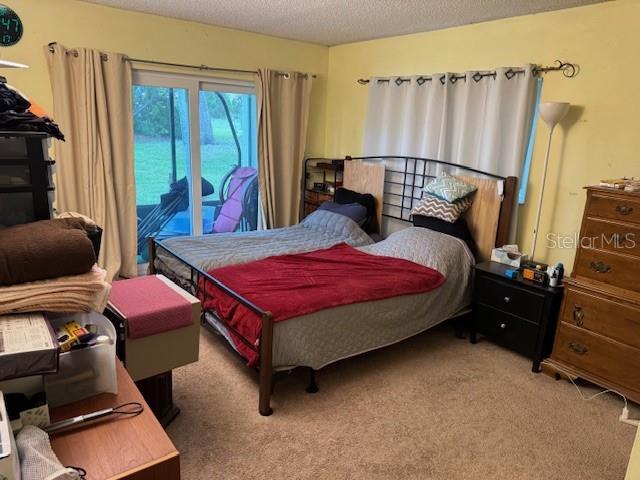 carpeted bedroom with a textured ceiling and access to exterior