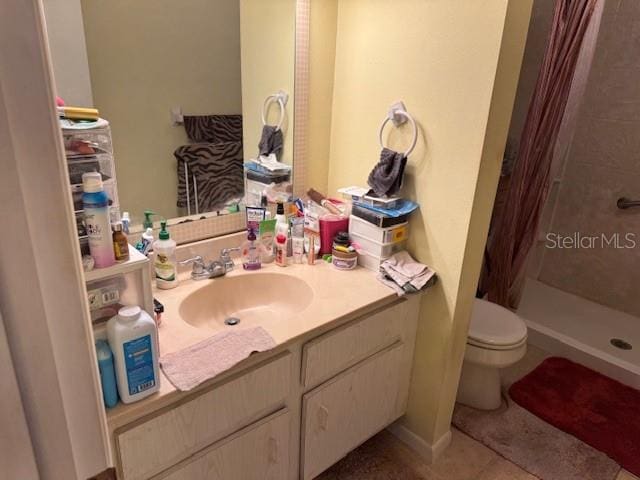 bathroom featuring toilet, a shower with shower curtain, tile patterned flooring, and vanity