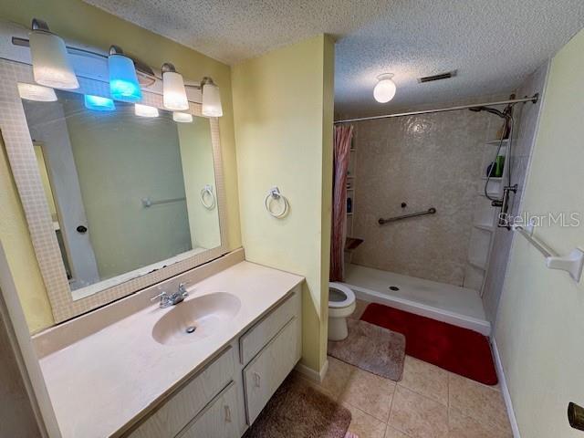 full bath with tile patterned floors, a textured ceiling, vanity, toilet, and a shower with shower curtain