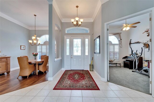 tiled entryway featuring ceiling fan with notable chandelier and crown molding