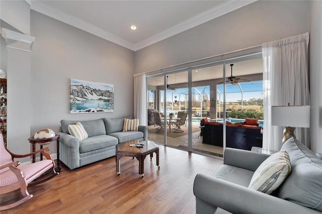 living room featuring wood-type flooring, ceiling fan, and ornamental molding