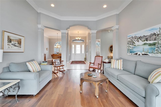 living room with decorative columns, a chandelier, hardwood / wood-style floors, and crown molding