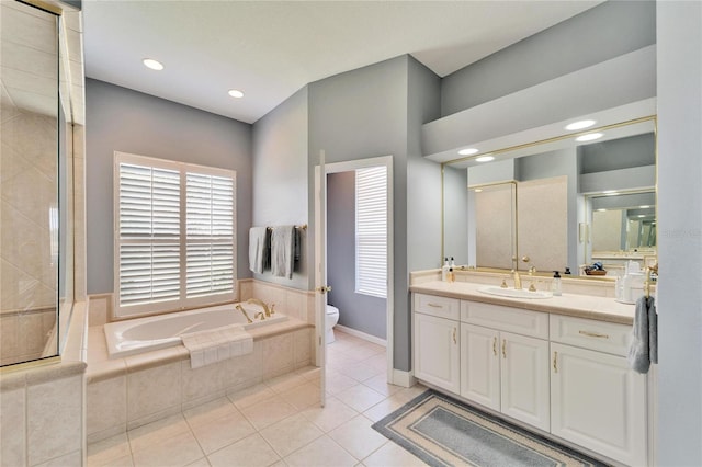 bathroom with tiled bath, tile patterned floors, vanity, and toilet