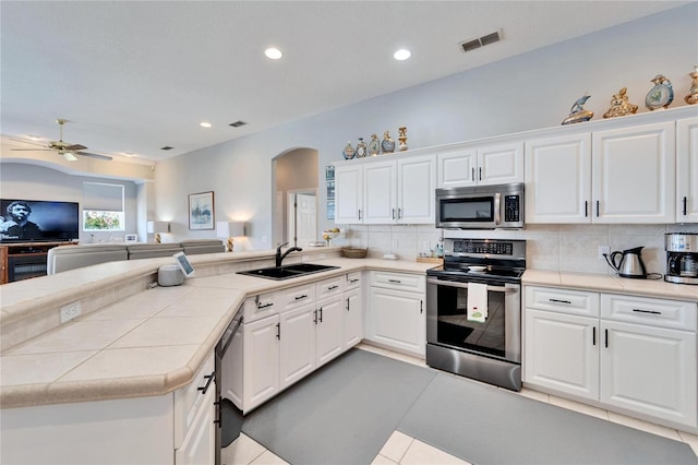 kitchen with sink, white cabinetry, stainless steel appliances, and tile countertops