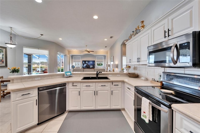 kitchen featuring appliances with stainless steel finishes, light tile patterned floors, white cabinets, sink, and kitchen peninsula