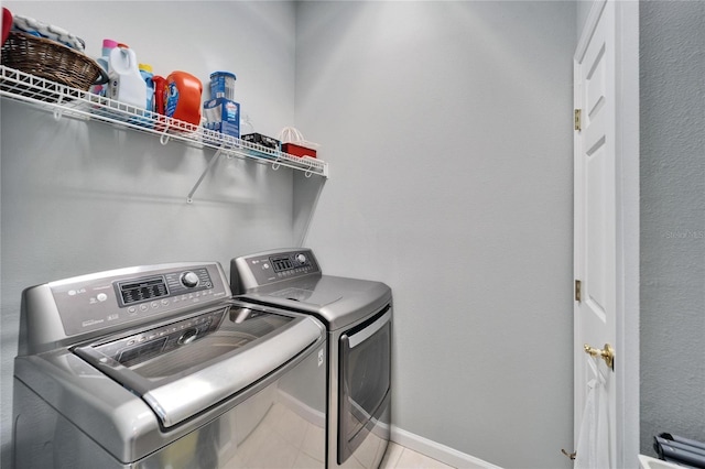 laundry area with separate washer and dryer and light tile patterned floors