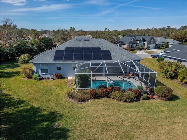 back of property with glass enclosure, a yard, and solar panels