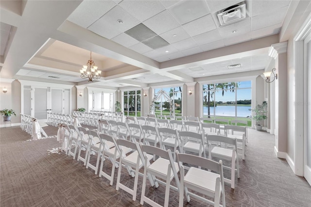 carpeted dining room with a paneled ceiling, a water view, and an inviting chandelier