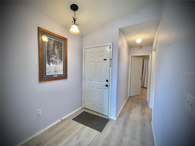 foyer entrance featuring lofted ceiling, light wood-type flooring, and a textured ceiling