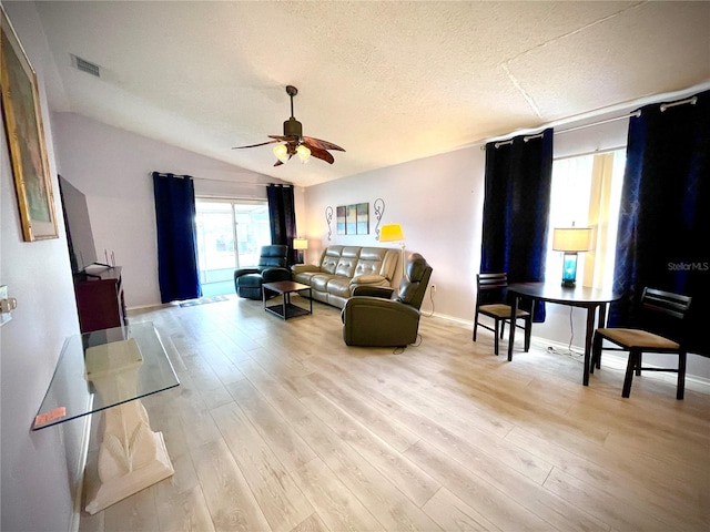 living room with lofted ceiling, ceiling fan, a textured ceiling, and light hardwood / wood-style floors