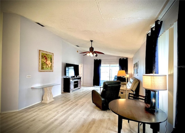 living room with ceiling fan, a textured ceiling, light wood-type flooring, and vaulted ceiling