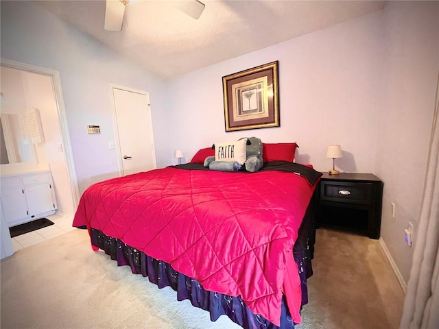 bedroom featuring ceiling fan, connected bathroom, light carpet, and lofted ceiling