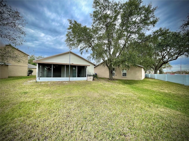 rear view of property featuring a sunroom and a yard