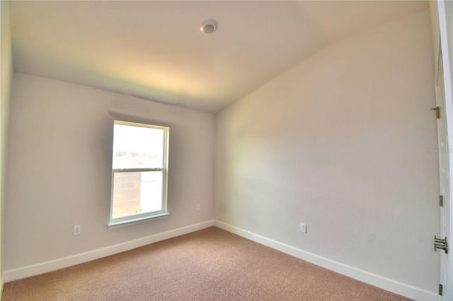 empty room with vaulted ceiling and carpet flooring